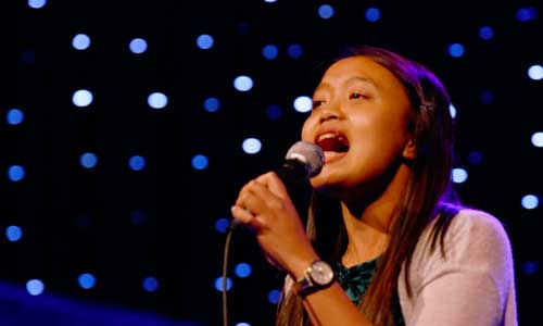 young Malaysian woman sings into a microphone