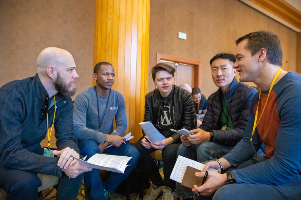 2 American men study the bible in a circle with 3 internationals